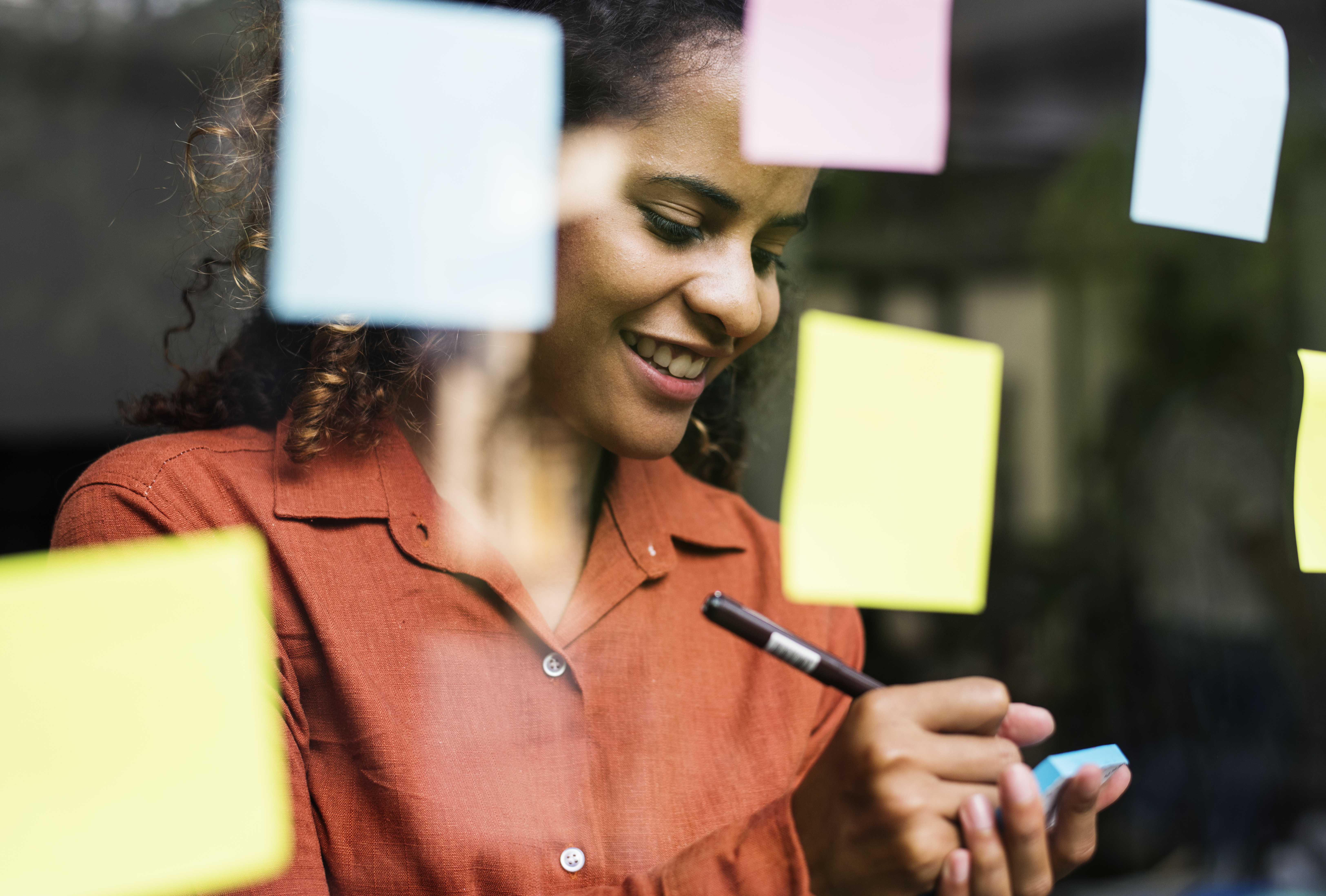 Woman smiling as she fills out sticky notes