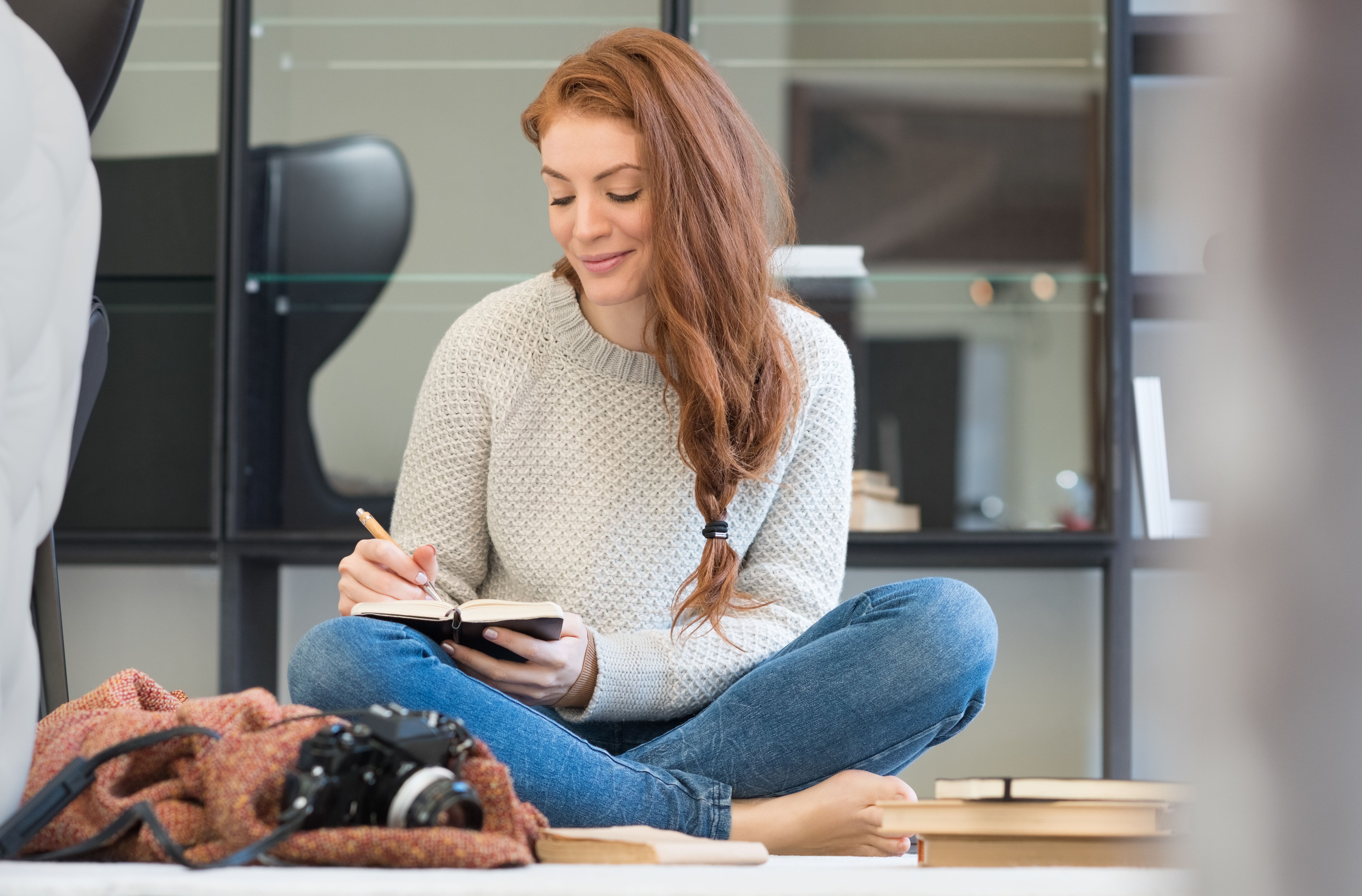 Woman writing on her knee sitting on the floor