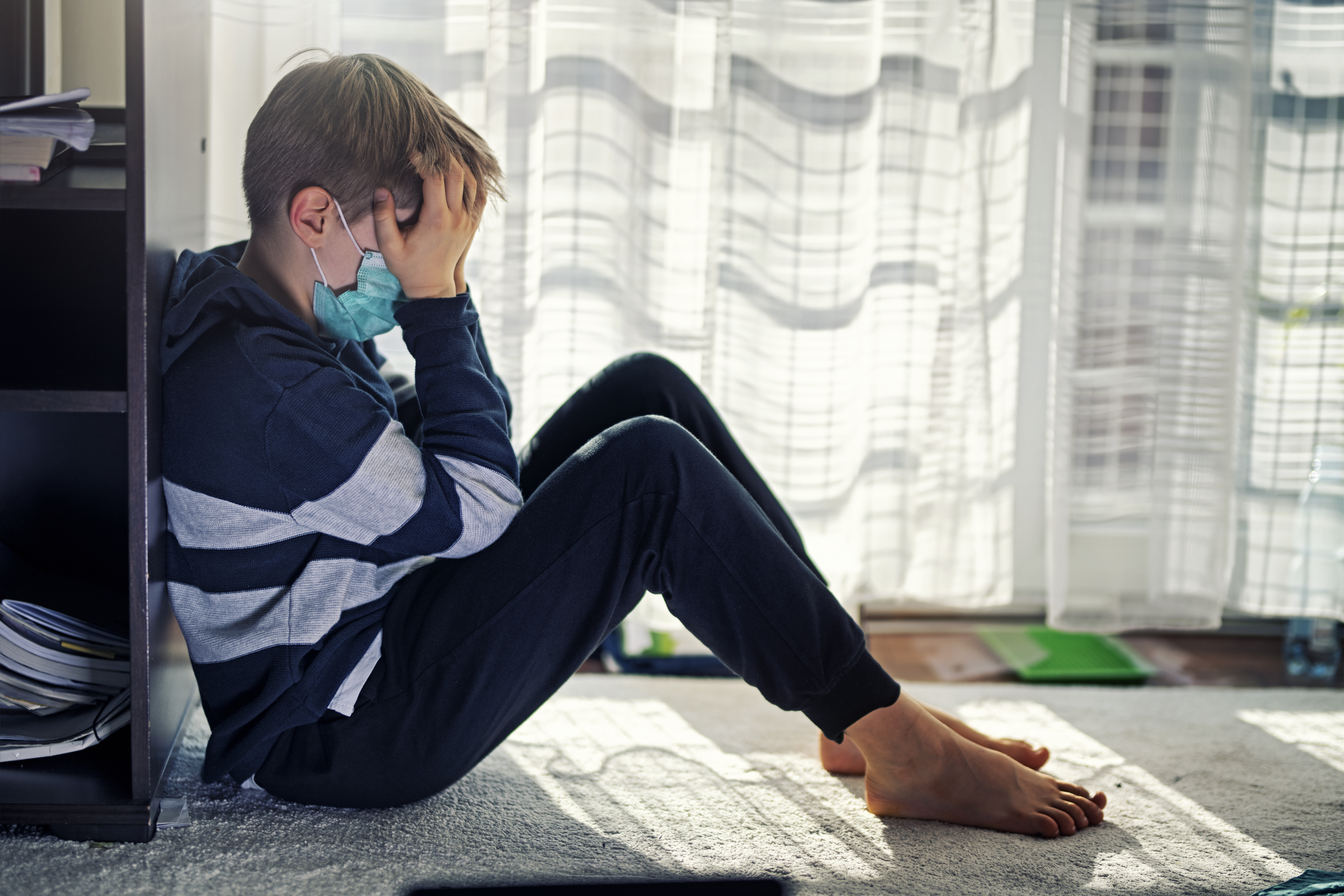 Child with mask with head in his hands looking anxious