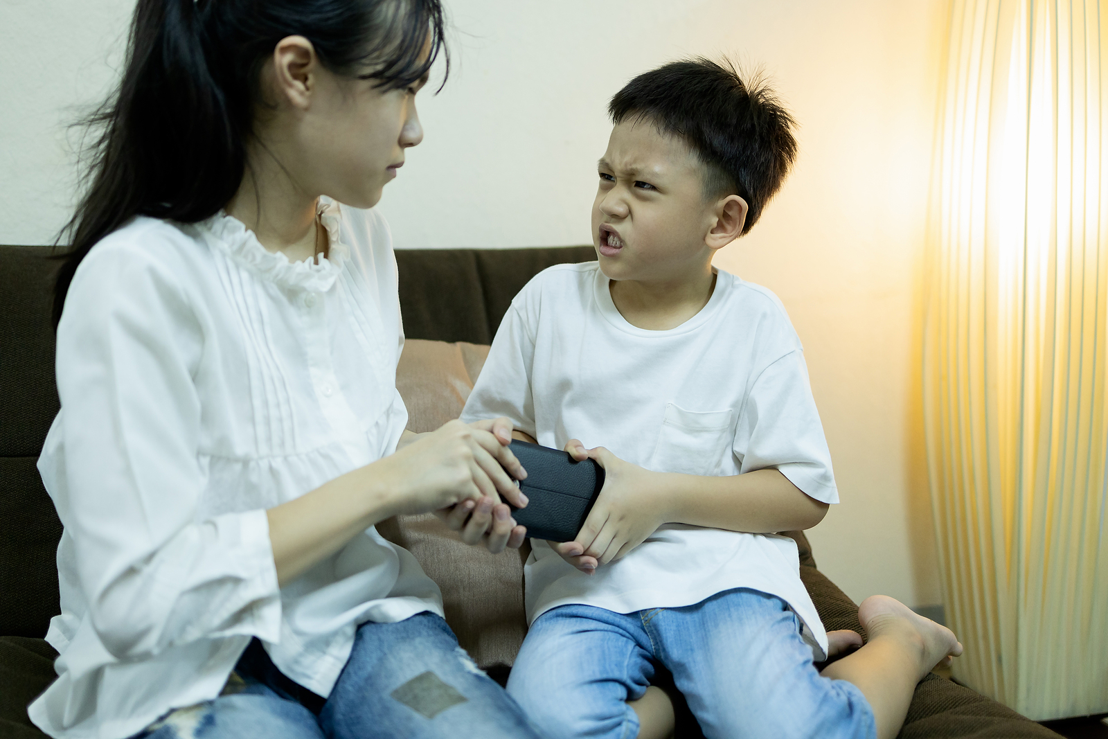 two children fighting over a toy looking argry