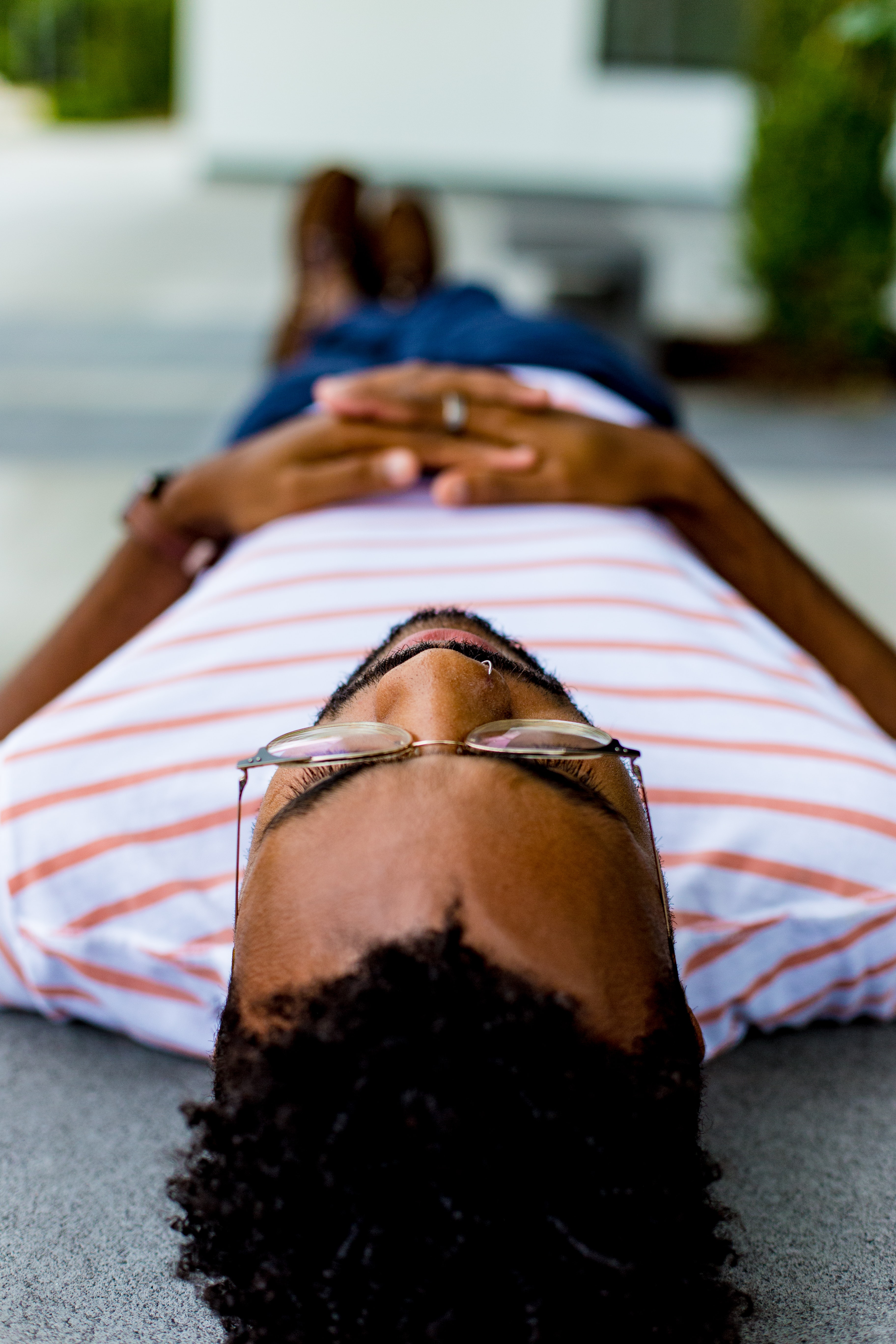 Image of black man laying on ground with legs crossed and hands resting on his abdomen