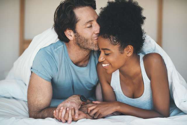 man kissing woman on the forehead