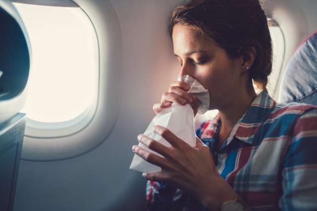 Woman hyperventilating into a bag on an airplane