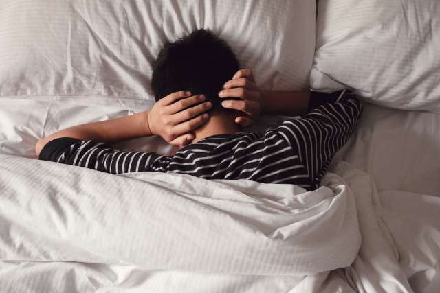 A young boy lays in bed. This reflects conversations had in teen therapy in St. Louis, MO. Our teen therapists in St. Louis, MO offer CBT for teens and help teens with anxiety See how online teen therapy in Missouri can help.