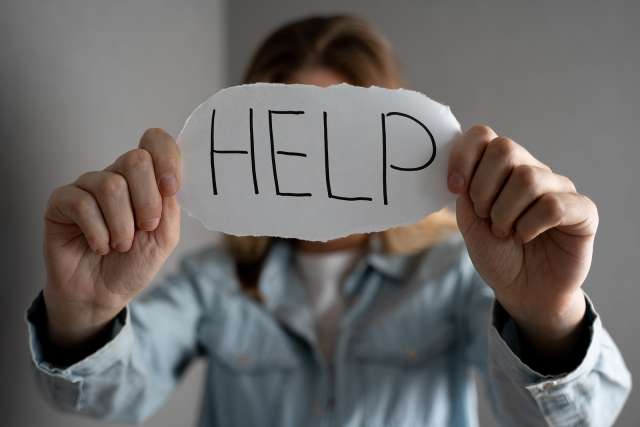 A woman holds a sign reading "help." This relates to concepts of therapy in St. Louis, MO. Our therapist in St. Louis, MO offer effective therapy in St. Louis, MO.