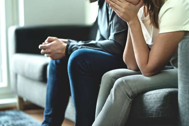 A couple sits next to each other on the couch. This relates to concepts of marriage counseling in St. Louis, MO. Our marriage counselors in St. Louis, MO offer couples counseling. 