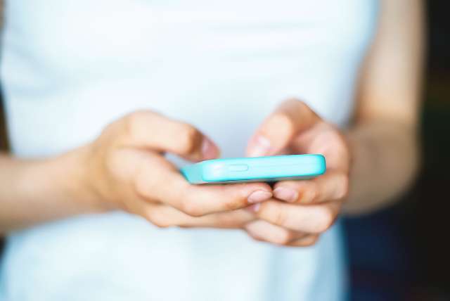 A person uses a phone. This relates to concepts teen therapy in Kansas City, MO. 