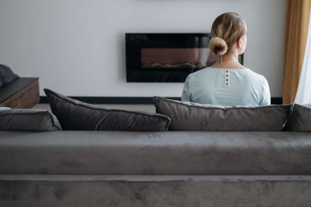 Woman seeking help looks out window from her living room 