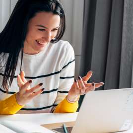 A woman uses a laptop while smiling. This demonstrates concepts of therapy in St. Louis, MO. We have therapists that can provide online therapy in Missouri and therapy in St. Louis, MO. 