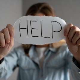 A person holds a piece of paper that reads "help". This relates to concepts of sexual assault. Therapy in St. Louis, MO can help. 