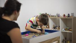 Boy playing in sand with therapist