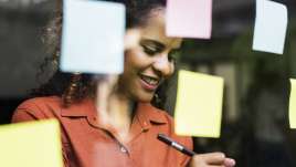 Woman smiling as she fills out sticky notes