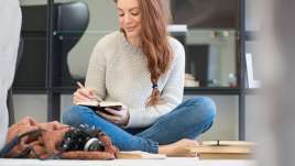 Woman writing on her knee sitting on the floor