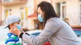 A mom helps a son with a mask. This relates to concepts of child therapy in St. Louis, MO. Our child therapist in St. Louis, MO provide therapy for children.